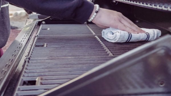 A man cleans a gas grill before storing it