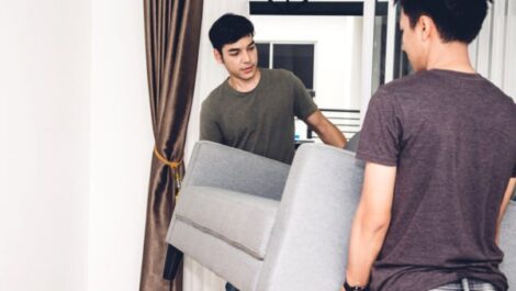 Two boys moving a couch in a home