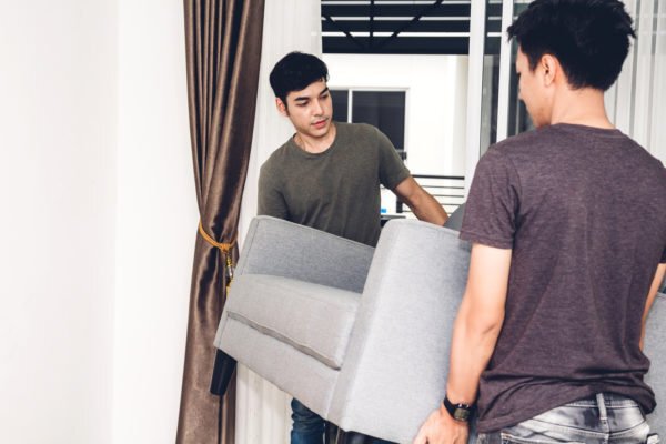 Two boys moving a couch in a home