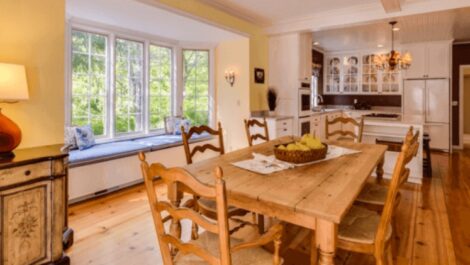 A home kitchen and dining space from the perspective of the dining area, including a dining room table set for four.
