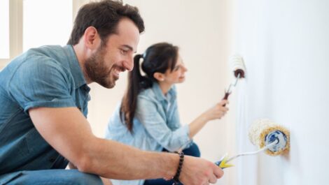 A man and woman happily painting a room to add value to their home.