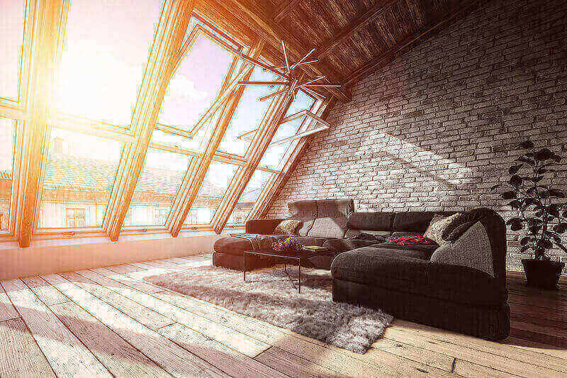 A spacious attic turned into a living room with a large couch and panoramic windows.