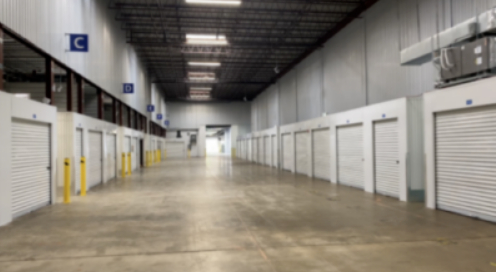 The interior hallway of a storage unit facility, featuring several storage unit entrance doors.