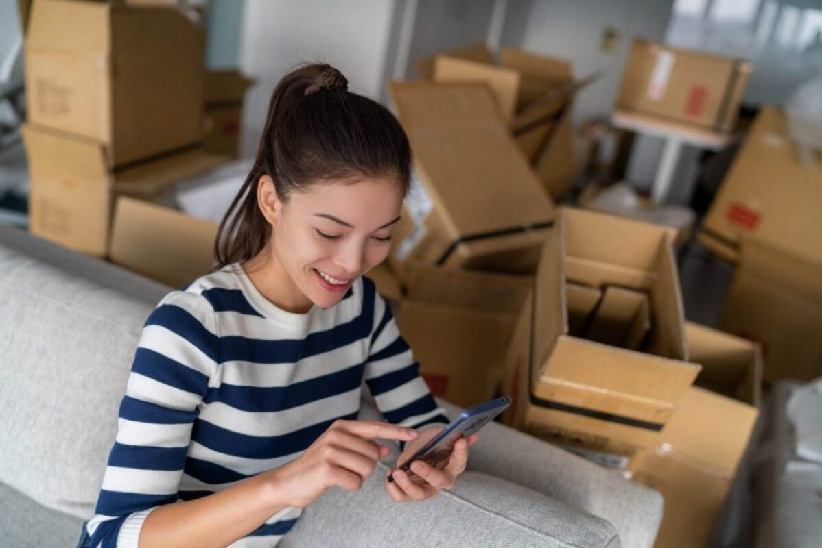 A young woman using a moving app while packing.