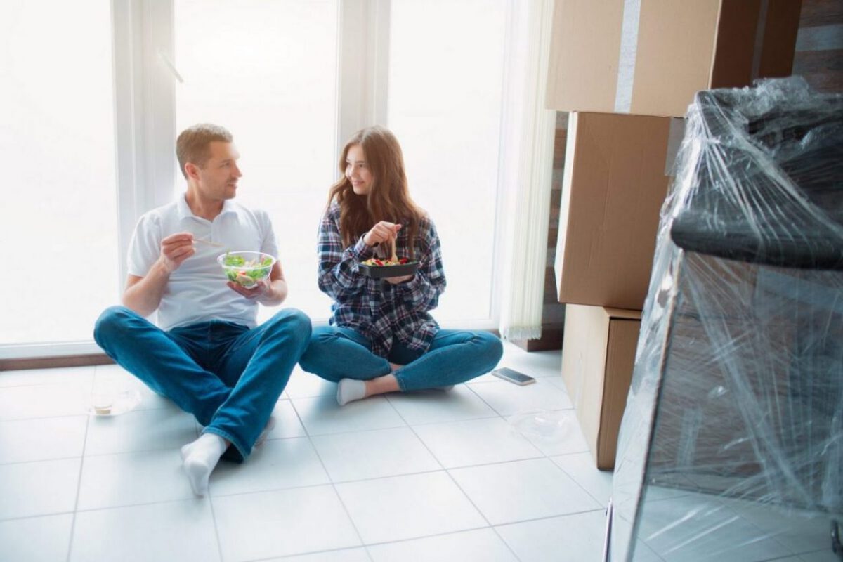 A couple eats dinner while packing for a move.