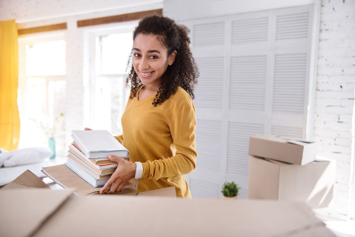 Woman packing books into boxes in her dorm room