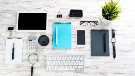 A neatly organized desk of items including a keyboard, notepad, and tablet.