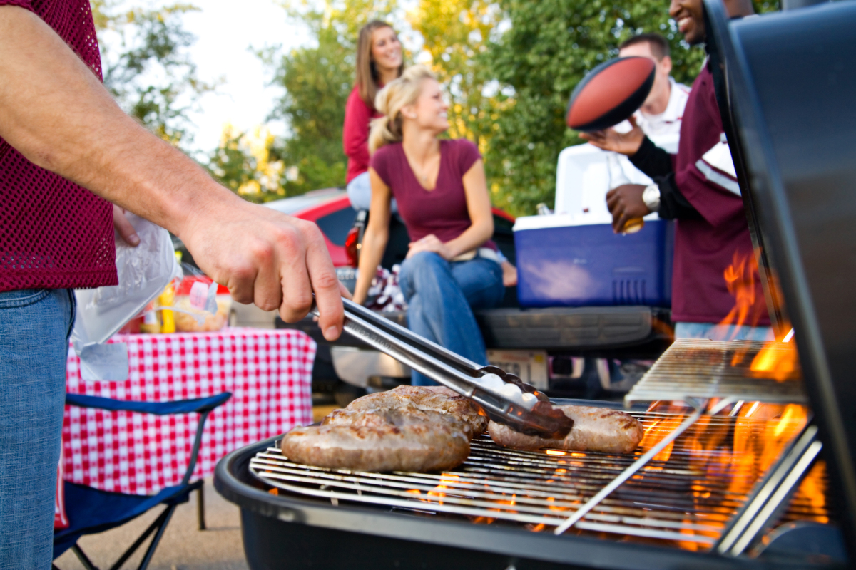 A group of people tailgating and grilling bratwurst