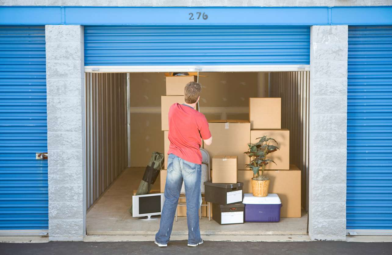 Individual pulling the closing latch on a filled storage unit's door.