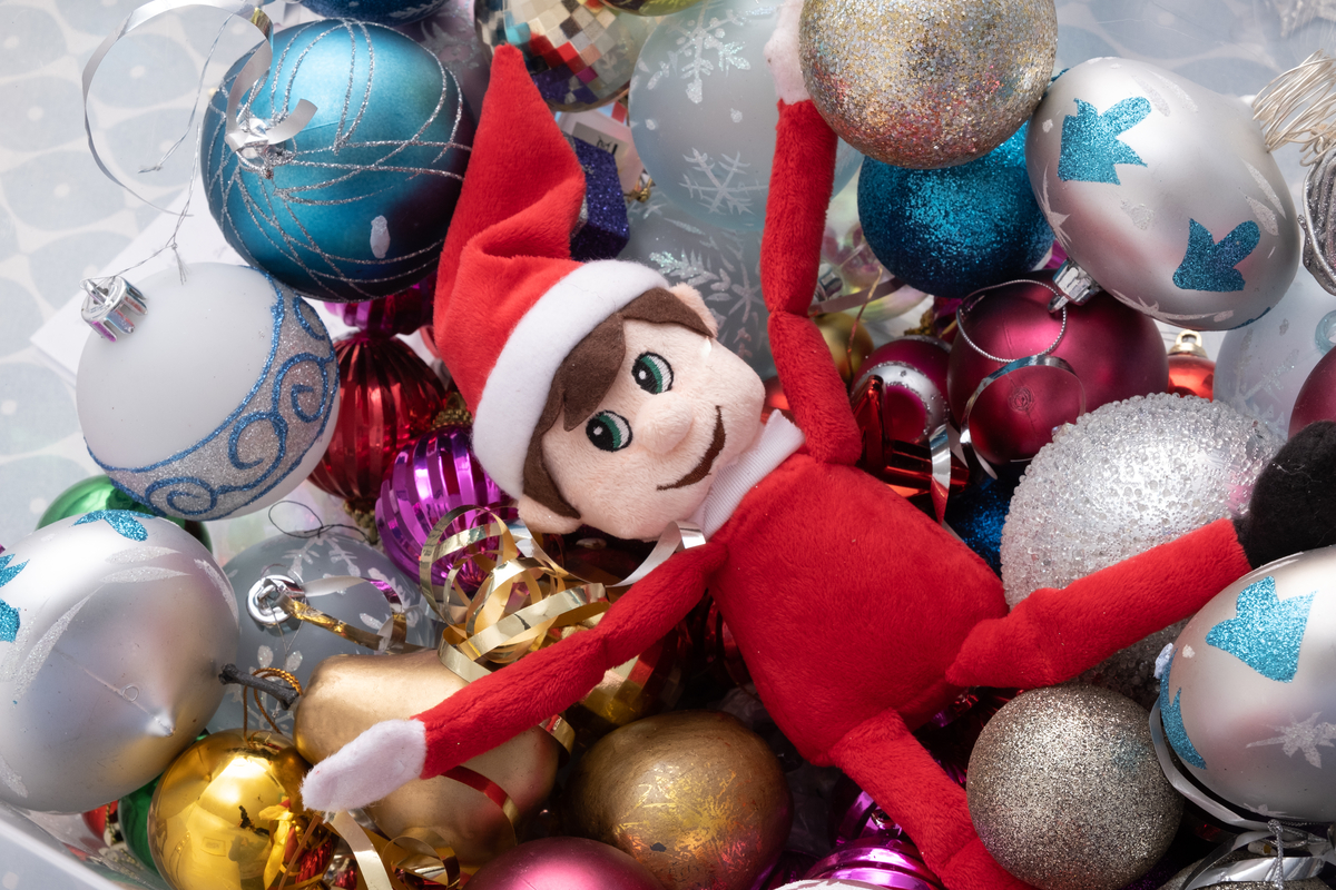 Elf on the shelf doll in pile of Christmas decorations