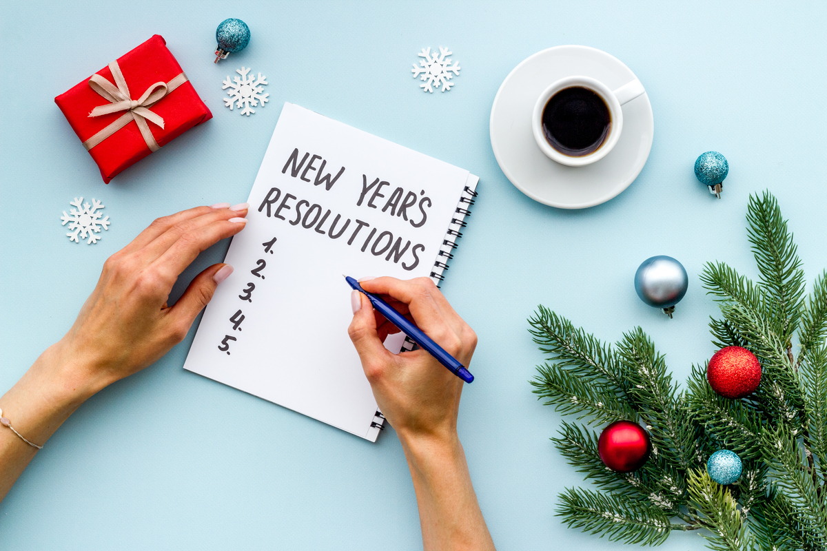 Photo of person making a new years resolution list with christmas decorations around them