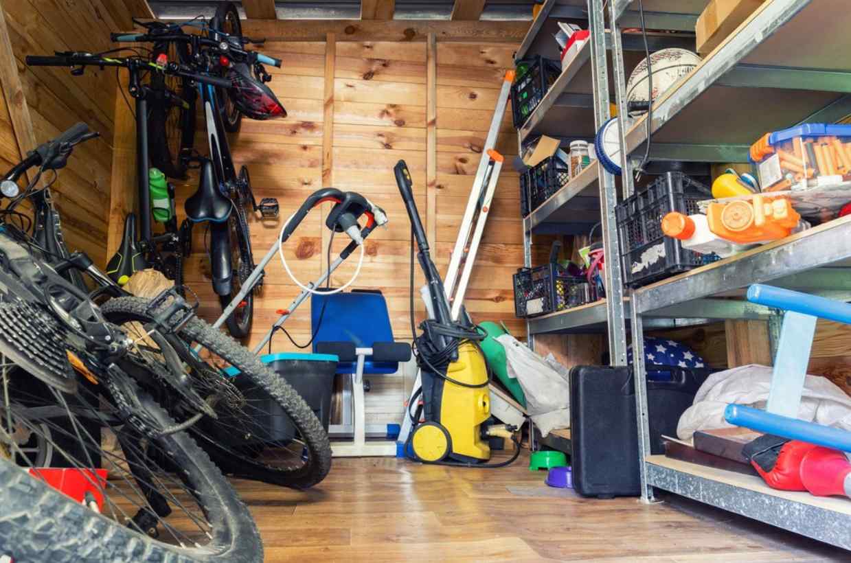 Interior of an unorganized storage space, including a bike and cleaning supplies on the floor.