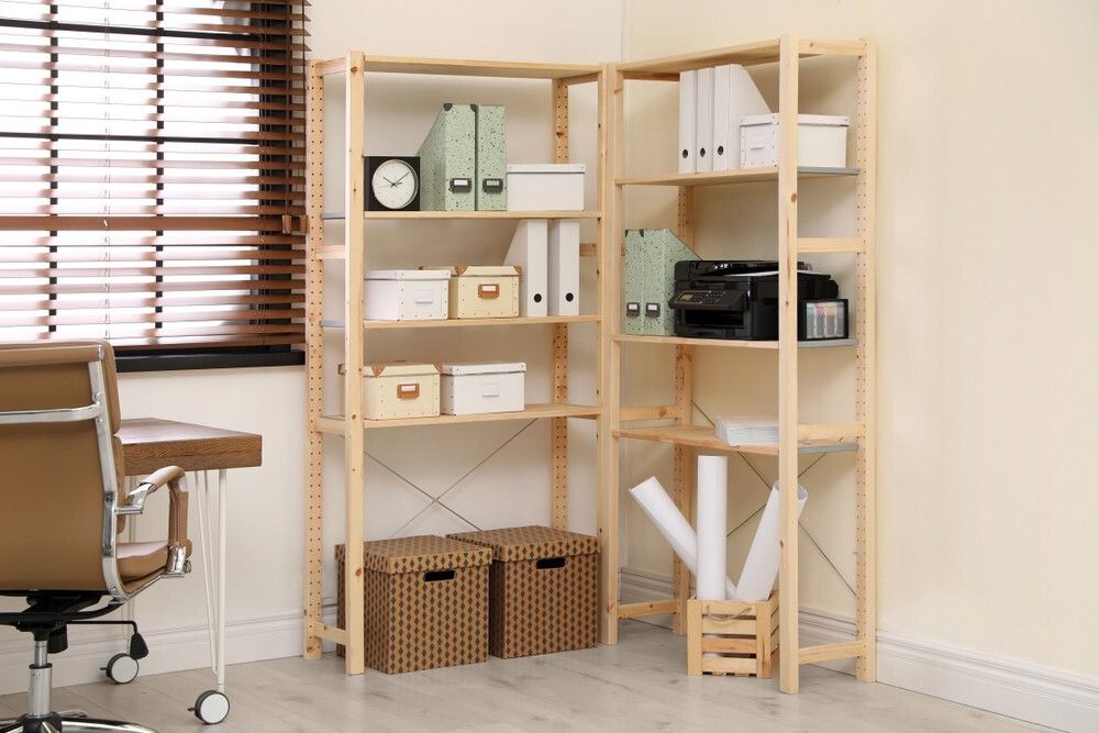 Photo of the corner of an interior office space, including a desk, chair and organized shelving space.