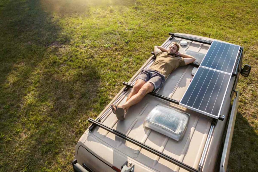 Man lying on his back and relaxing on the roof of his van.