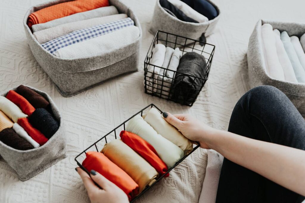 Someone organizing their clothes in different storage bins.