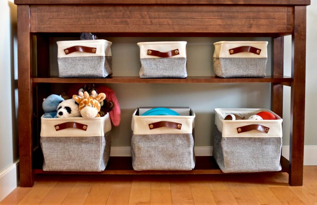 Storage baskets under a table filled with toys and stuffed animals.